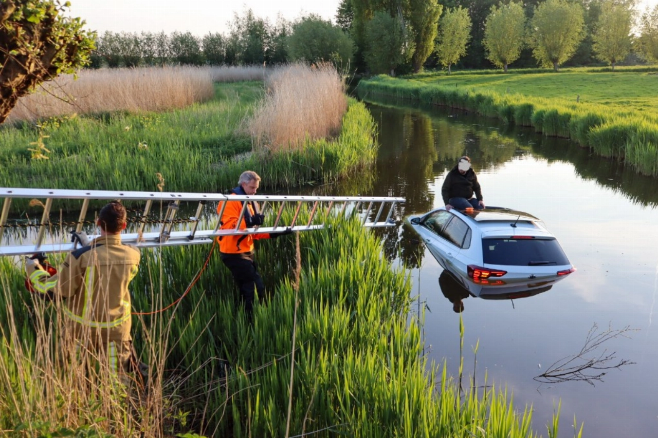 Auto te water, man van dak gered