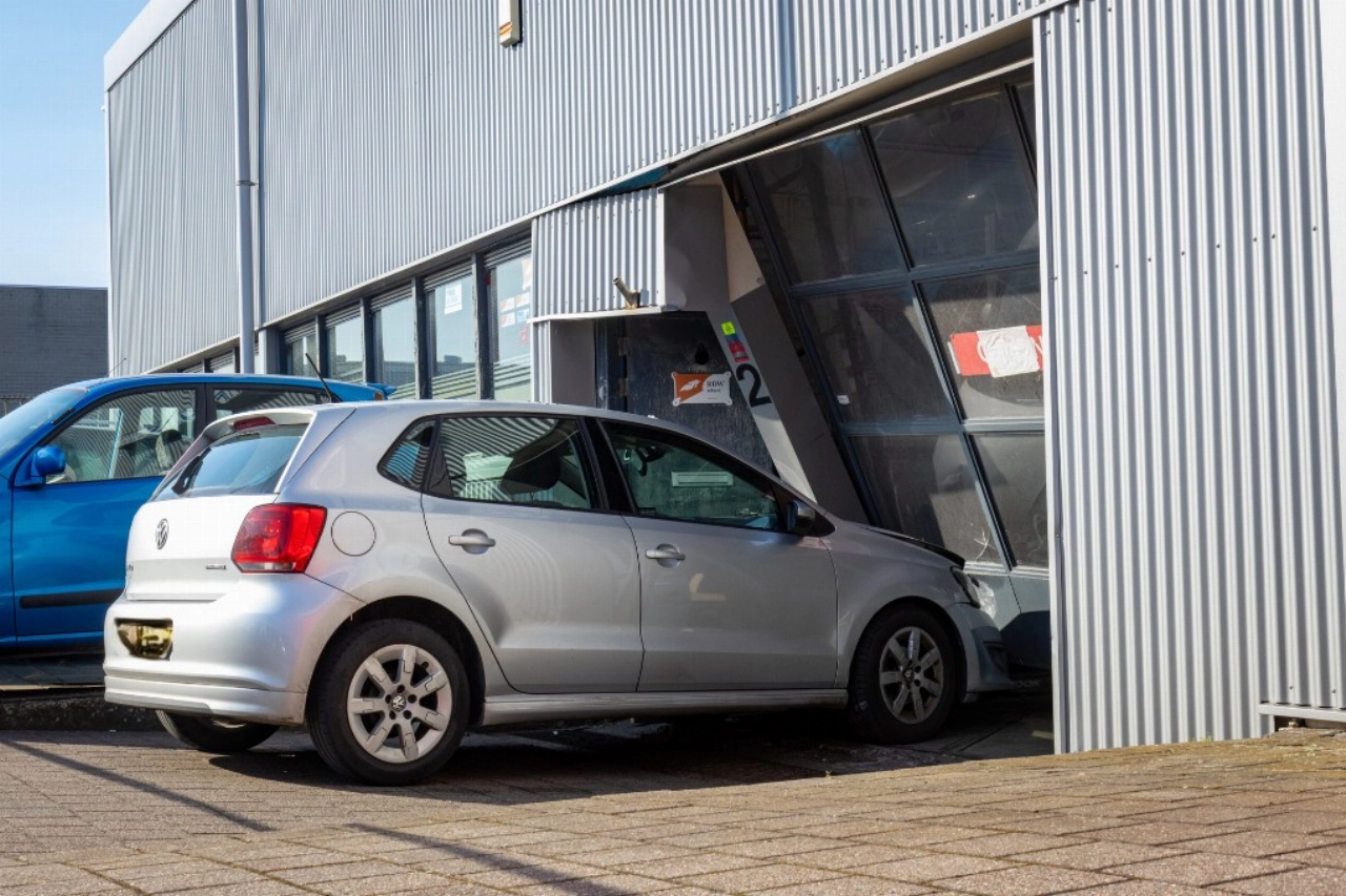 Auto rijdt dwars door roldeur garagebedrijf heen