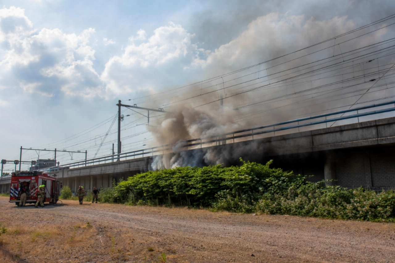 Grote rookwolken bij brand onder spoorwegviaduct