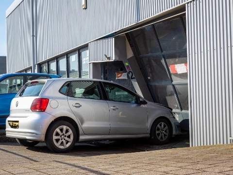 Auto rijdt dwars door roldeur garagebedrijf heen