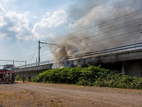 Grote rookwolken bij brand onder spoorwegviaduct