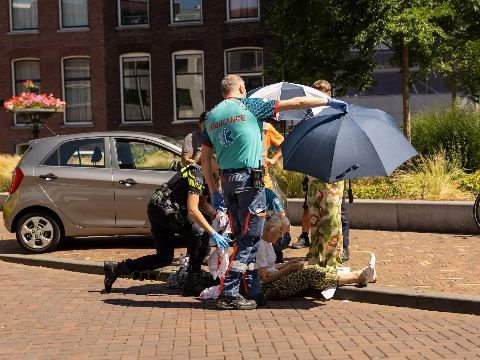 Oudere vrouw op fiets komt lelijk ten val na aanrijding met scooter