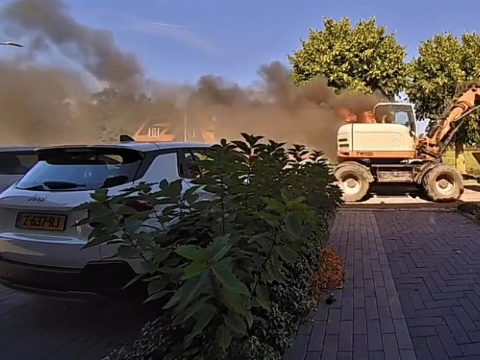 Brandende graafmachine rijdt door straat na plotselinge brand